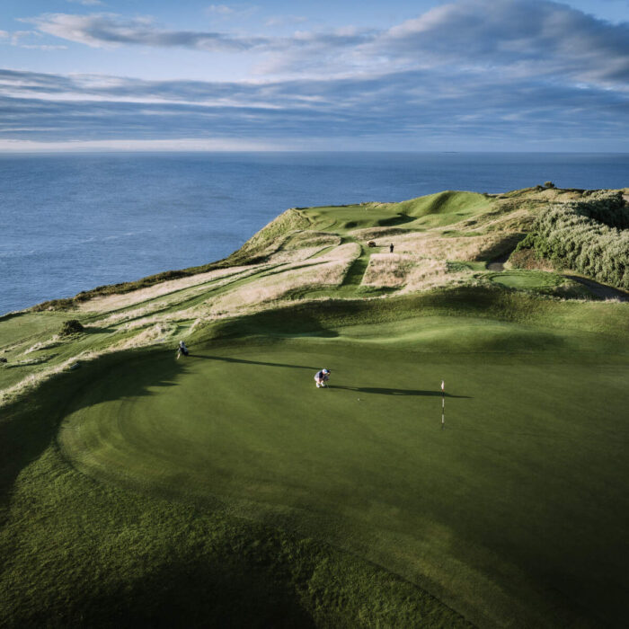 A scenic view of the 2nd hole, known as the 'Gun Hole', at Old Head Golf Links in Kinsale, County Cork, Ireland, overlooking the rugged coastline and Atlantic Ocean.