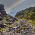 The stony path leading towards Ireland's highest Mountain, Carrauntoohil in the MacGillicuddy Reeks with a rainbow in the background,  Co. Kerry, Munster, Ireland.