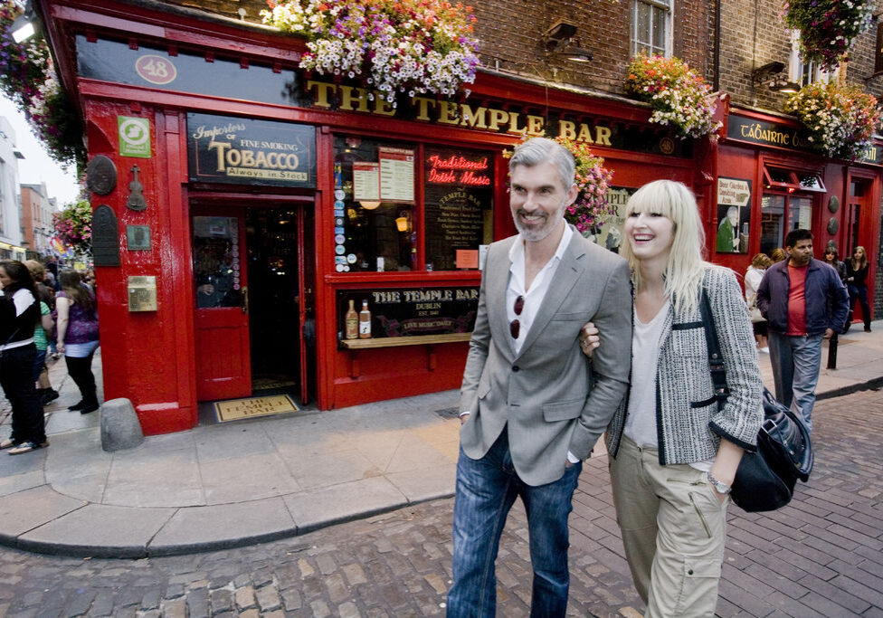 couple walking down city streets in front of pub